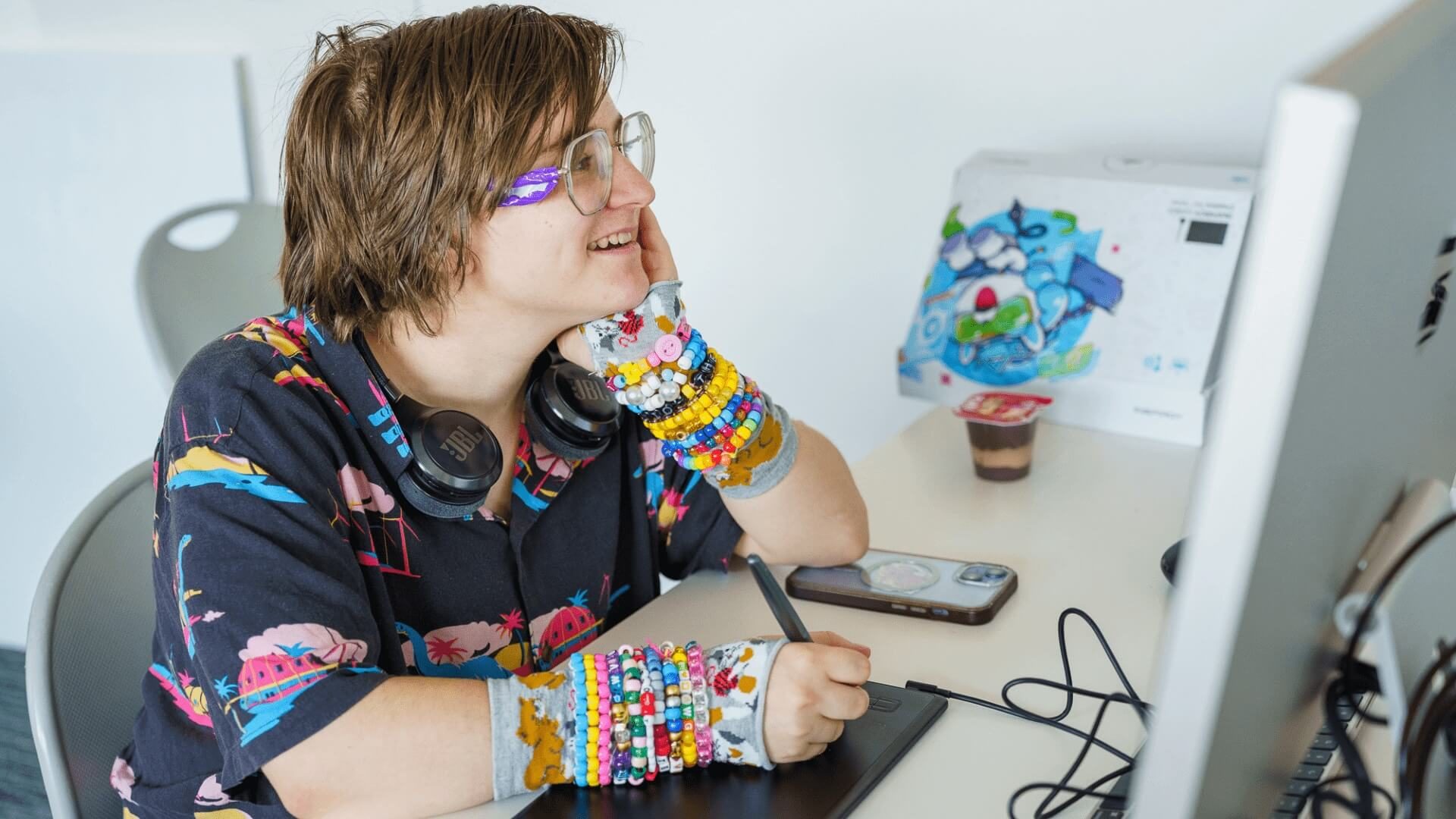 student sits in front of a computer, smiling